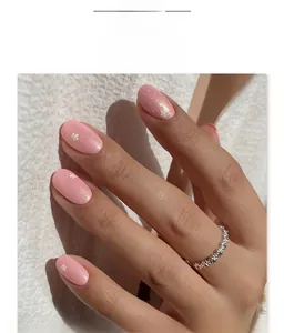 Macro shot of pink glitter press-on nails with white floral pattern and oval shape