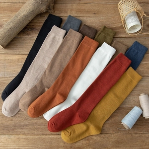 Japanese style cotton long calf socks in various colors displayed on a rustic wooden background