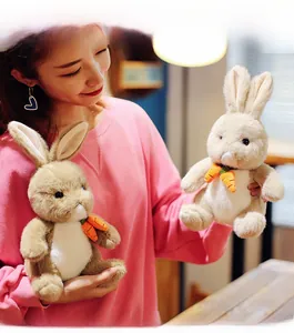 Detail of plush bunny toys in brown and cream with carrot charms held by a model