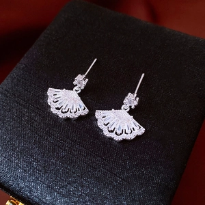 Macro shot of fan-shaped silver earrings with sparkling cubic zirconia on black jewelry box
