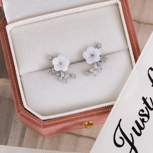 Detailed macro of floral stud earrings with shell petals in a pink velvet jewelry box
