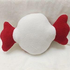 Detailed view of candy-shaped plush toy with soft white sherpa fabric and red ties