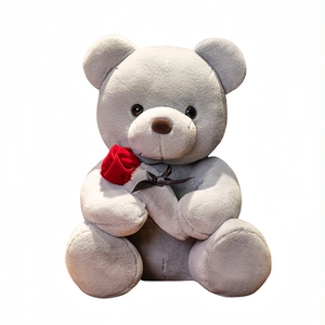 Oso de peluche gris y blanco con una rosa roja y lazo sobre un fondo blanco