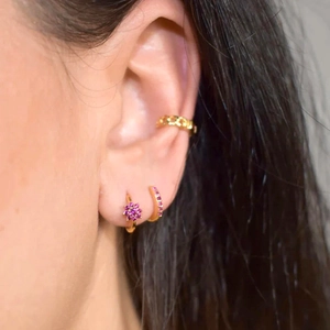 Golden flower earrings set with pink zircon stones worn on model ear for display