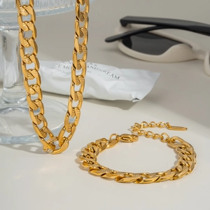 Minimalistisches vergoldetes Titan-Panzerketten-Set mit Textur auf weißem Tisch