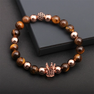 Detailed macro view of tiger eye beads and rose gold crown pendant with black zircon