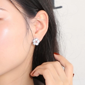 Close-up of a silver flower stud earring with micro-pave crystals on a model ear