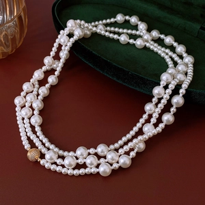 Vue macro d'un collier de perles multicouche avec fermoir sphérique doré serti de zircons