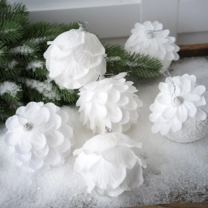 Close-up of six white glitter flower-shaped Christmas balls on artificial snow