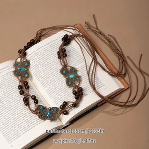 Close-up of bohemian woven belt with butterfly charms on vintage book background