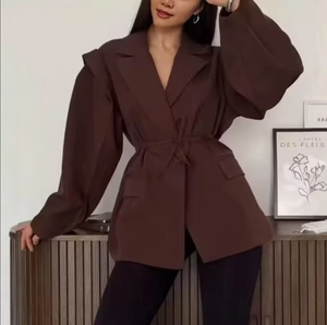 Détail du blazer marron foncé avec revers larges, ceinture à nouer et manches lanternes