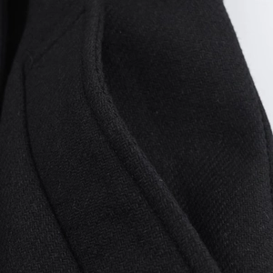 Detailed macro view showing the textured wool blend fabric and stitching on a black coat