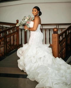 Detail of fishtail wedding dress with sequined lace bodice and tiered organza ruffles
