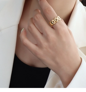 Detailed view of wide golden watch-chain link ring on finger for a chic look