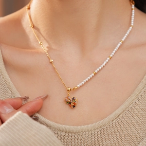 Detail of 18k gold beaded necklace with pearl chain and rainbow gemstone heart pendant