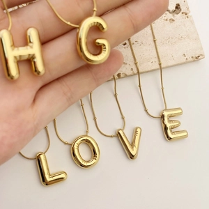 Golden 3D balloon alphabet necklace with polished metal letter pendants on a bead chain