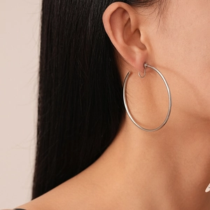 Close-up of minimalist silver hoop earrings on model showing geometric metallic style