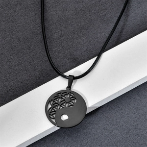 Detail of black stainless steel Tai Chi pendant with Flower of Life geometric pattern