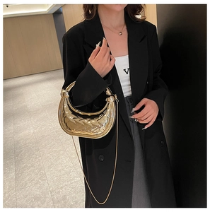Golden crescent handbag with woven texture and metal chain strap on model