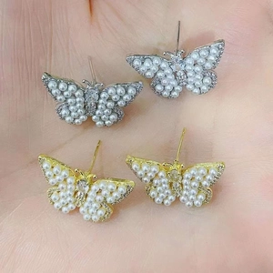 Detailed view of butterfly stud earrings with pearls and crystals on hand for scale