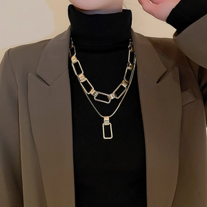 Detail view of a double-layered gold geometric chain necklace with rectangular pendant