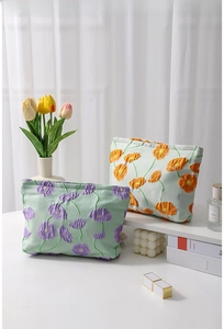Close-up of canvas makeup bags with floral embroidery and branded woven labels