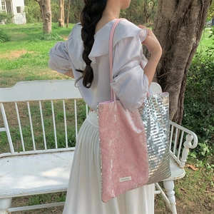 Pink and silver sequin patchwork tote bag worn over shoulder in a garden setting