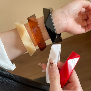 Close-up of geometric resin bangles in marble beige, amber, black, and red set