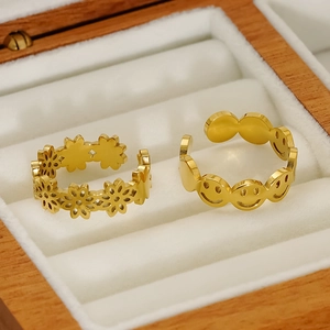 Detail of gold hollow flower and smiley face stainless steel ring set in a wooden box