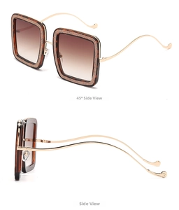 Detail of square oversized tortoiseshell sunglasses with wavy gold temples and brown lenses