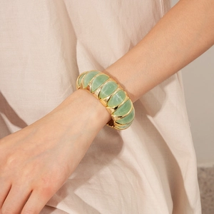 Detailed view of vintage stretch bracelet featuring green resin insets and gold frame