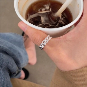 Dettaglio anello a maglia d'argento sulla mano che tiene una tazza di caffè alla moda