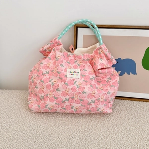 Dettaglio della borsa tote rosa a fiori con manici in corda blu e etichetta logo