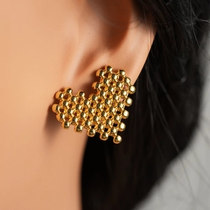 Macro shot of gold heart-shaped stud earrings featuring a textured woven bead design