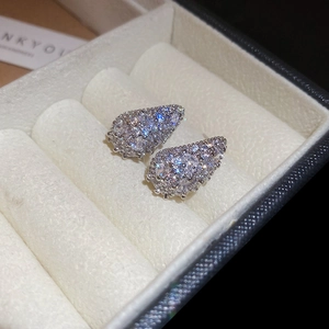 Macro shot of silver teardrop stud earrings with pave-set zircons in a jewelry box