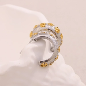 Detail of two-tone 18K gold plated stainless steel C-shaped earrings with floral pattern