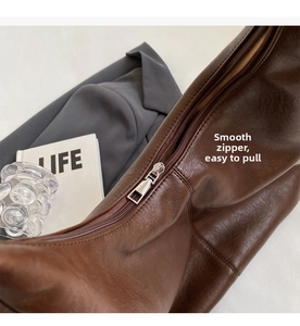Close-up of smooth silver zipper detail on a premium brown leather tote bag