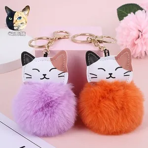 Detail of plush cat pompom keychains in purple and orange with PU leather cat charms