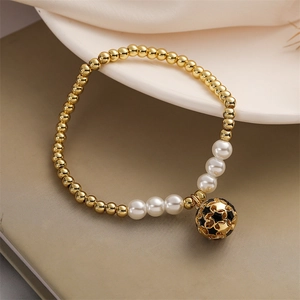Détail du bracelet perles dorées et blanches avec pendentif étoile sur plat céramique