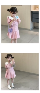 Detailed view of pink short-sleeve girls dress with white Peter Pan collar and pleated skirt
