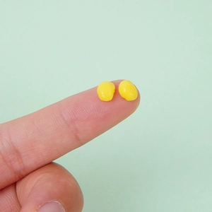 Realistic mini yellow corn kernels DIY handmade craft accessories shown on a fingertip