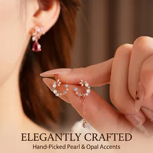 Rose gold flower drop earrings with blue crystals and pearls worn by a model