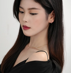 Close-up of a model wearing minimalist 18K gold bead chain necklace and hoop earrings