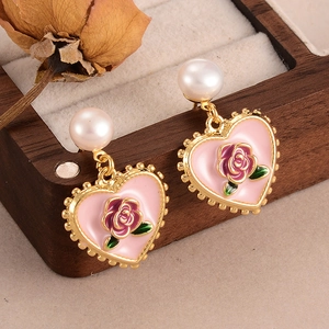 Vintage heart rose earrings with pearl studs on a rustic wooden jewelry box