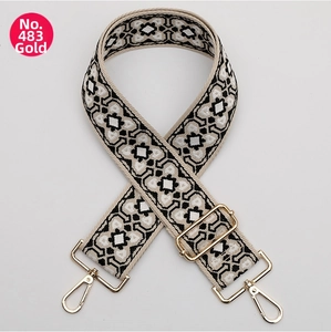 Close-up of black and white geometric woven strap with gold metal swivel hooks and buckle