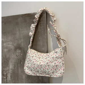 Detailed view of cream floral fabric shoulder bag with ruffle strap and zipper closure