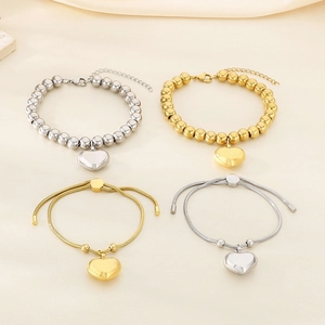Dettaglio di bracciali a perline con ciondolo a cuore placcati oro 18K e argento
