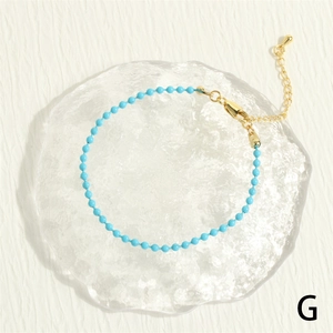 Detail of bohemian turquoise beaded bracelet with golden lobster clasp on a glass plate