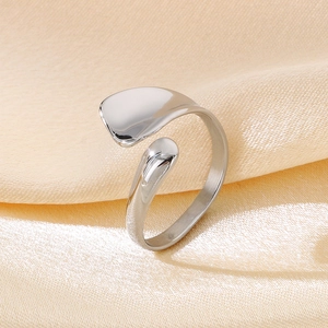 Macro shot of silver minimalist open ring with water drop design on soft beige fabric
