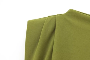 Detailed close-up of olive green dress featuring padded shoulder and pleated texture